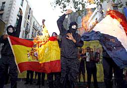 Radicales encapuchados queman una foto de los Reyes y la bandera de España.