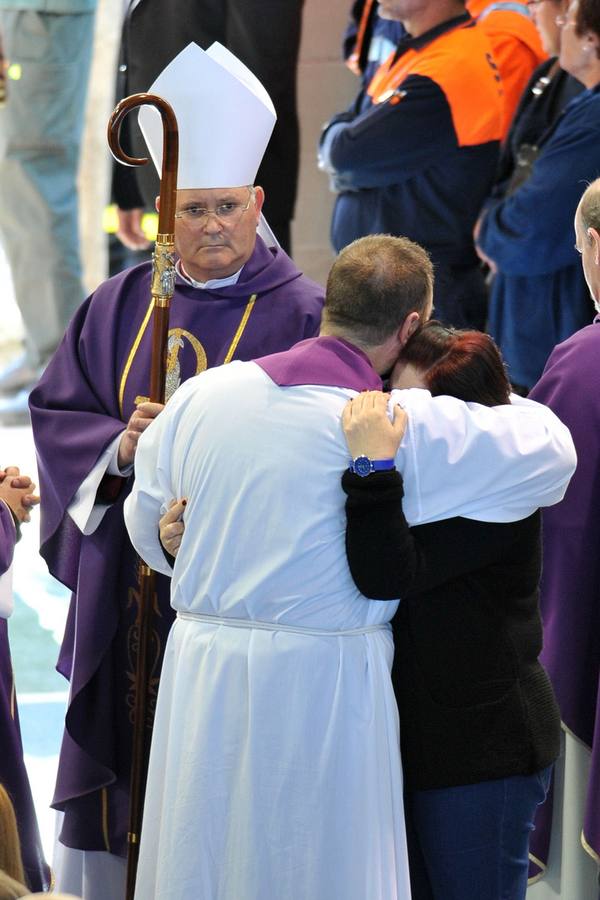 El obispo Lorca Planes ofició la misa funeral por los fallecidos. En la imagen, un sacerdote abraza a un familiar de las víctimas.