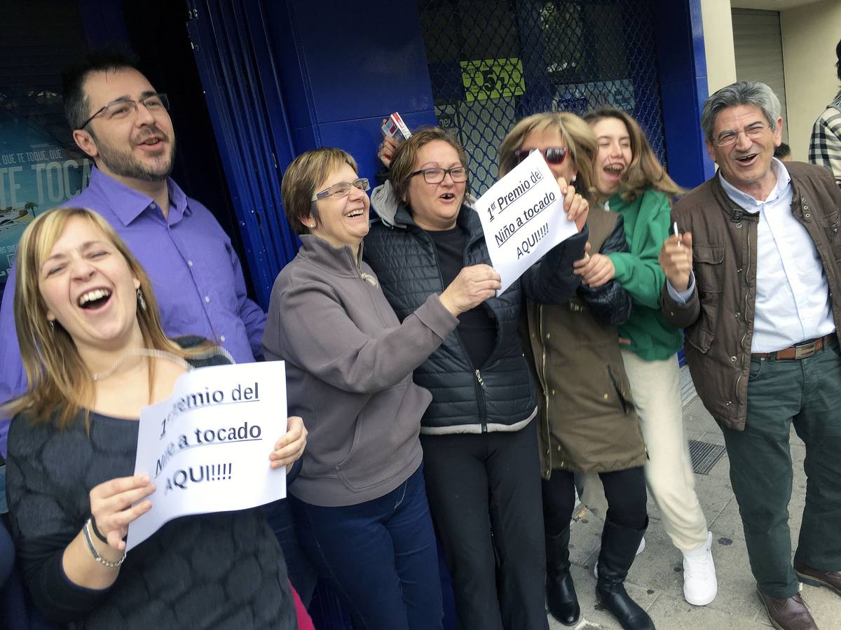 Varios afortunados con el primer premio del sorteo de El Niño lo celebran ante la administración de lotería Nº3 de la localidad castellonense de La Vall d'Uixo en el que compraron el 22.654.