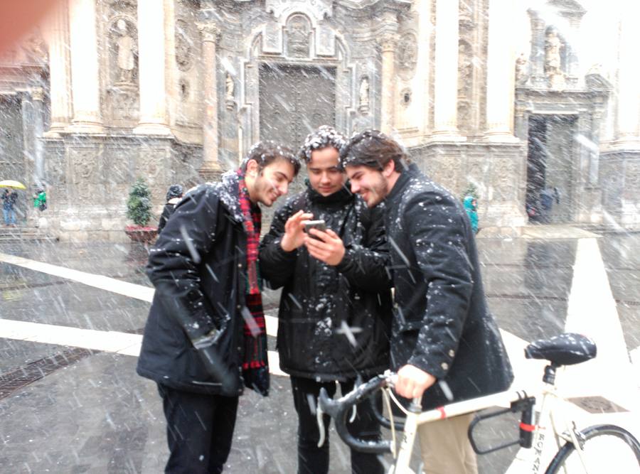 Tres jóvenes inmortalizan el momento en la puerta de la Catedral de Murcia.