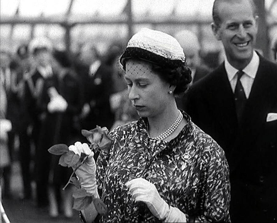 La Reina Isabel II de Inglaterra contempla una rosa en la Feria de las Flores de Chelsea acompañada de su esposo en 1960.