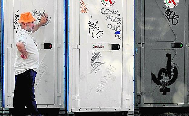 Un hombre espera en unos baños públicos callejeros. 