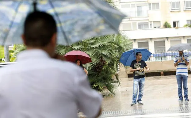 Vecinos de Murcia se protegen de la lluvia este miércoles. 