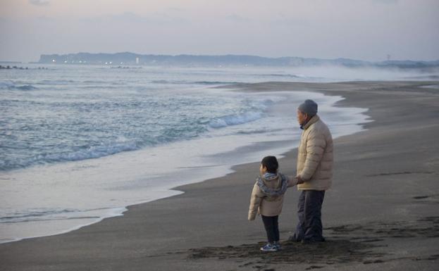 Un anciano contempla junto a su nieto el amanecer en la playa de Isumi (Japón).