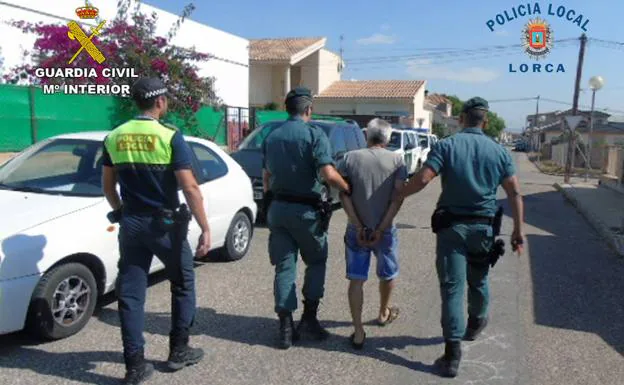 dos guardias civiles custodian a uno de los detenidos. 