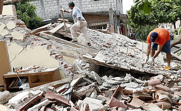 Dos hombres buscando entre los escombros tras el terremoto.