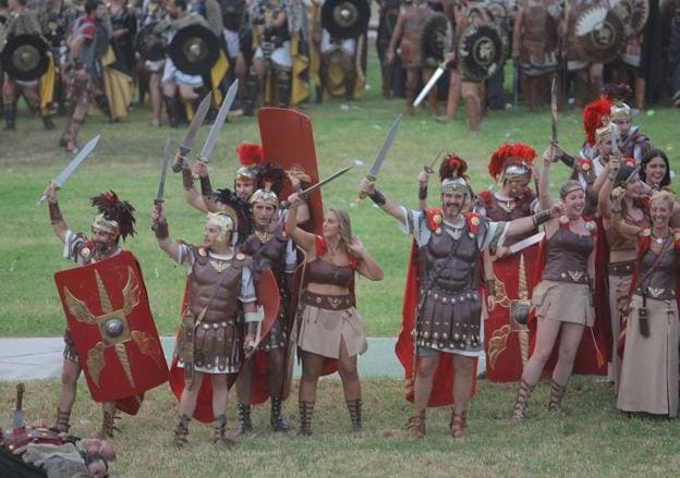 Legionarios romanos celebran, armas en alto, la victoria en la gran batalla, con enemigos vencidos a sus pies.