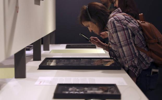 Una mujer observa algunos negativos que se pueden contemplar en la exposición 'Magnum: Hojas de contacto'. 