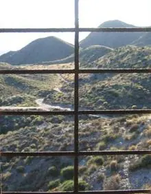 Imagen secundaria 2 - Un grupo de ciclistas recorriendo la senda, Cala Tocino, una playa de guijarros, y una fotografía del monte desde el interior del edificio abandonado.