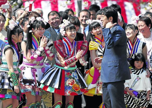 Mujeres de un grupo folclórico ríen con el primer ministro, Shinzo Abe, en una fiesta de primavera.