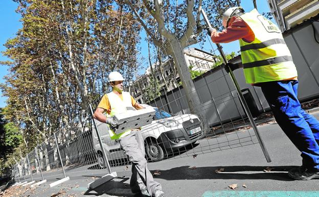 Dos obreros colocan las vallas para trabajar en un lateral del paseo Alfonso X.