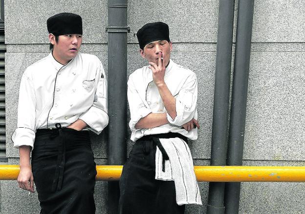 Dos trabajadores japoneses apuran un cigarrillo a la puerta de su empresa.