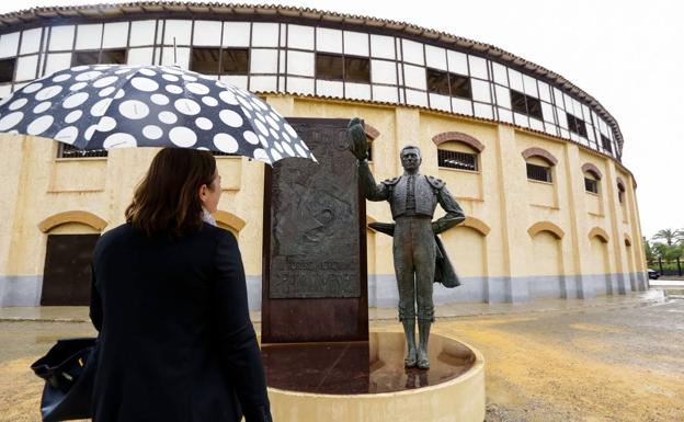 Una mujer observa la estatua de Pepín Liria junto a a la fachada de la plaza de toros de Lorca.