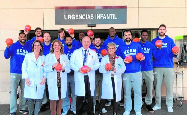 Los jugadores del UCAM y personal sanitario, en la puerta de urgencias pediátricas de La Arrixaca.