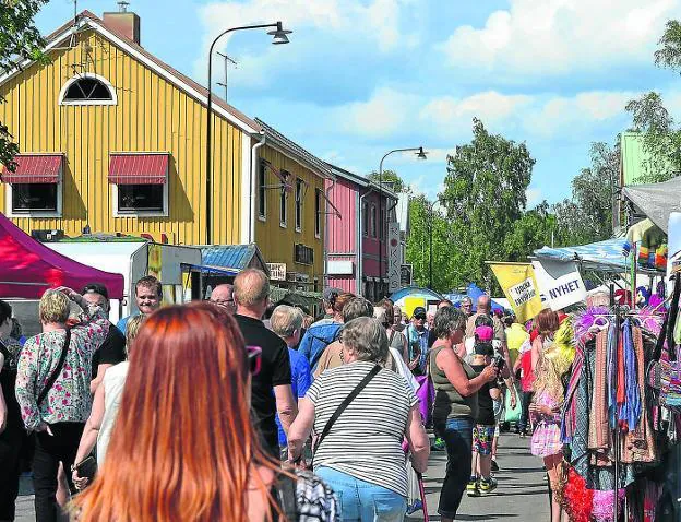 Paseantes caminan por una calle de Överkalix en un día estival de mercado. 
