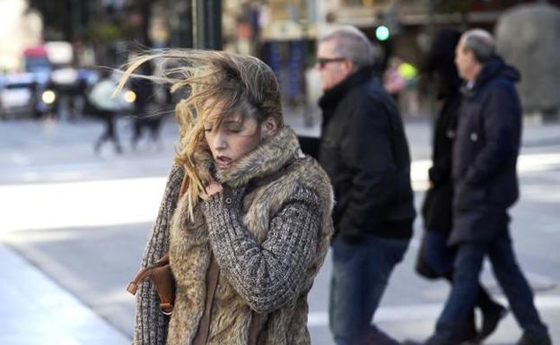 Una mujer se protege del viento en una calle de Murcia. 