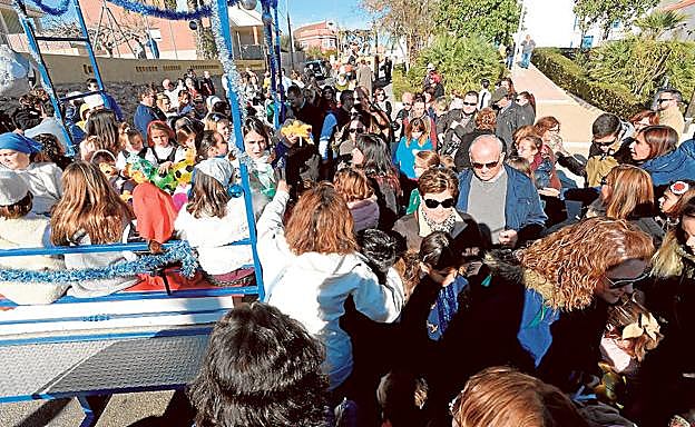 Los niños subidos a una de las carrozas arrojan caramelos durante la cabalgata, en Perín.