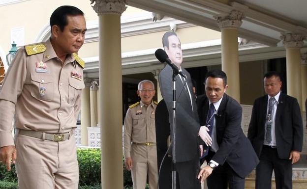 El primer ministro de Tailandia, Prayut Chan-o-cha, se despide de los periodistas mientras deja una fotografía suya a tamaño real.