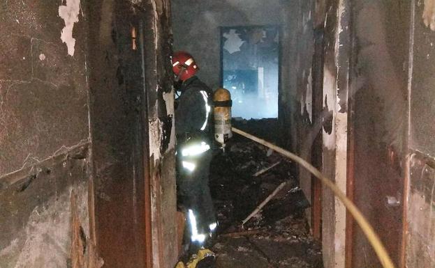Un bombero trabaja en las labores de extinción del incendio en el interior de la vivienda, situada en la calle Burgos, de Molina de Segura. 