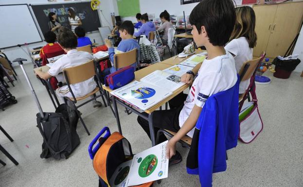 Un niño guardando un libro en su mochila.