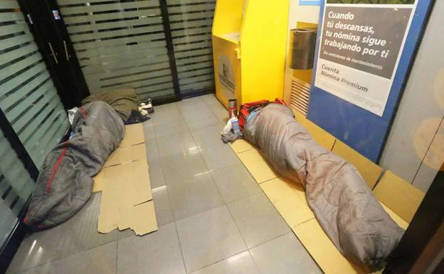 Dos personas sin hogar duermen en un cajero, en una fotografía de archivo.