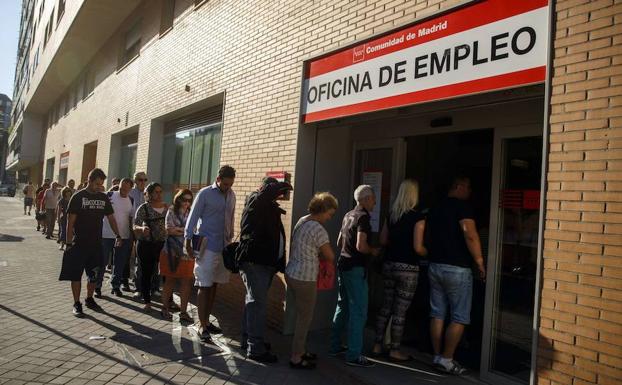 Numerosas personas esperan para entrar a una oficina de empleo en Madrid.