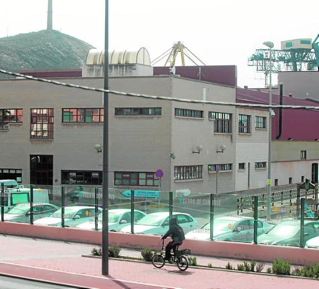 Un ciclista pasa frente al edificio de talleres del puerto.