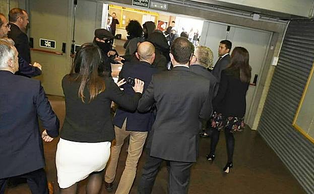 Varias personas desalojan a los encapuchados del acto. 