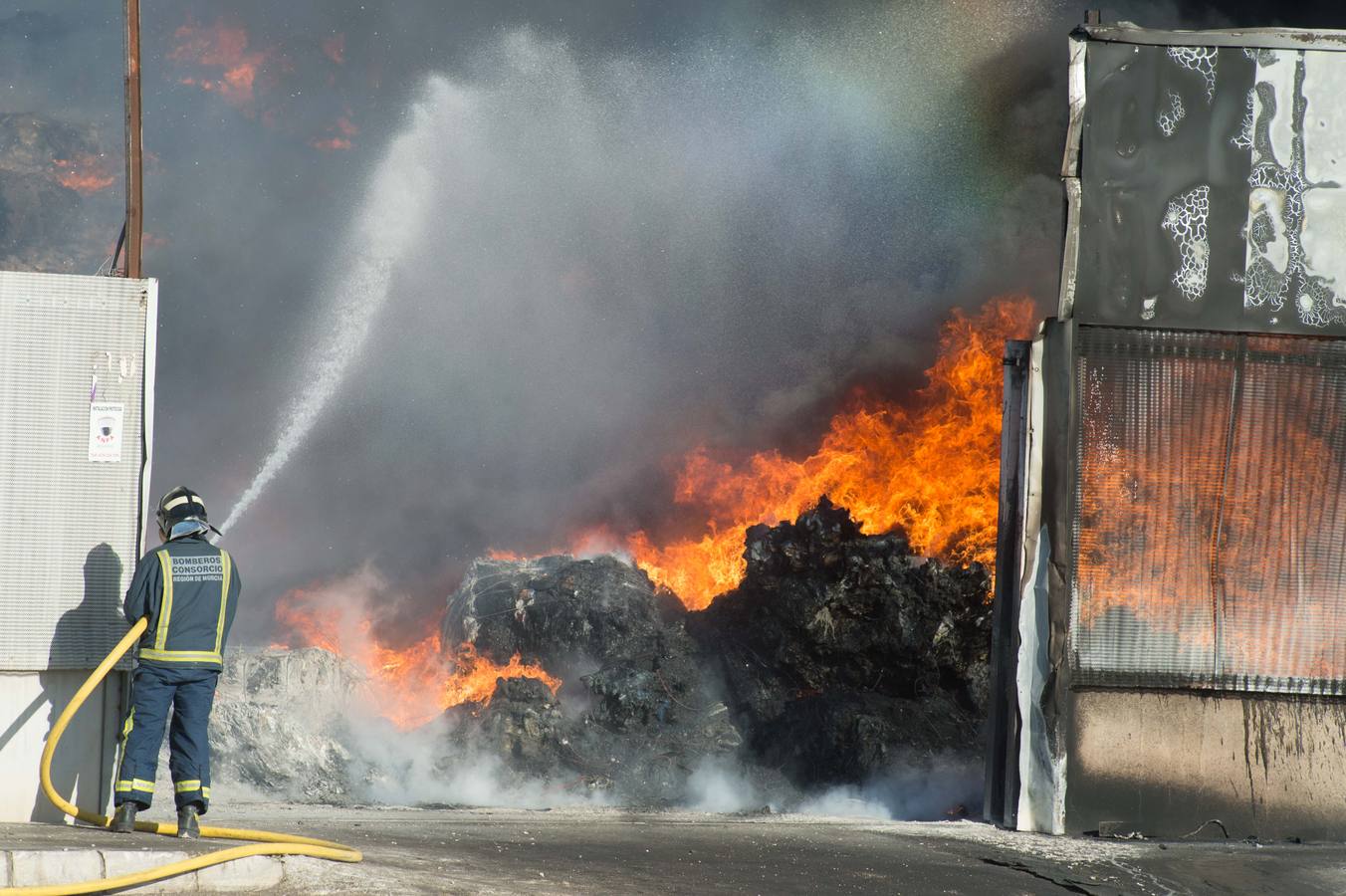 Los bomberos trabajan en la extinción de un incendio en una empresa de reciclaje de residuos en Santomera que ha originado una gran columna de humo a primera hora de la tarde, alrededor de las 16.30 horas de este miércoles.