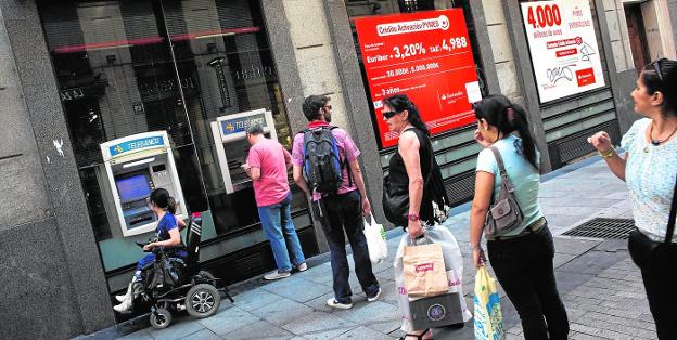Usuarios de un banco aguardan para sacar dinero de cajeros automáticos.