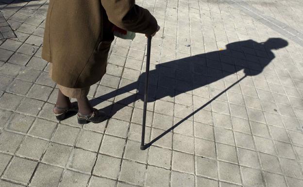 Una anciana camina con ayuda de un bastón.