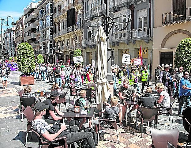 Vecinos y turistas toman un aperitivo, mientras la manifestación pasa por la calle del Carmen.
