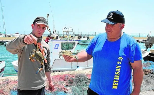 Dos pescadores muestran ejemplares capturados de cangrejo azul en la laguna. 