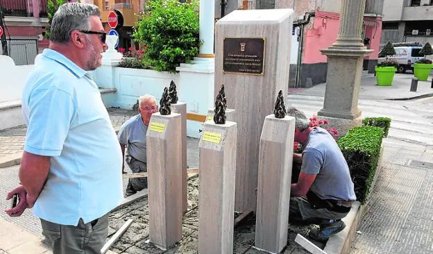 Un vecino observa cómo los operarios instalan el monolito.