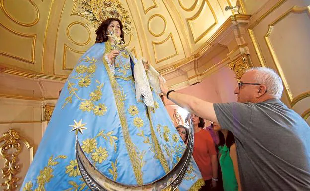 El párroco y varias feligresas, ayer, contemplan la talla, ya en su altar.