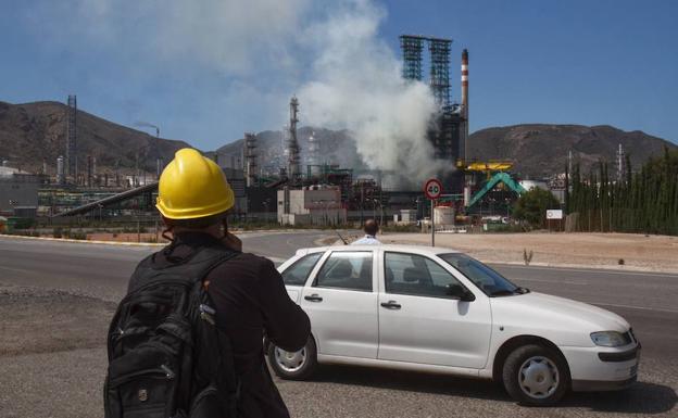 Operarios observan la nube de humo que sale de la refinería.