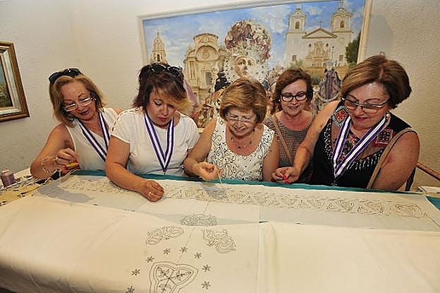 Varias mujeres ayudan a bordar el manto junto a la Corte de Honor de la Virgen.