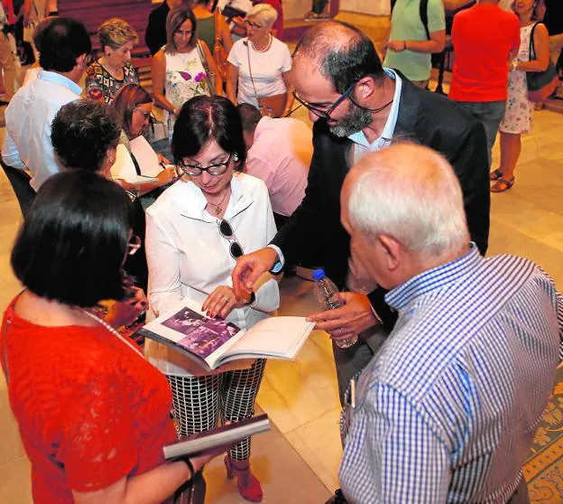 A la izquierda, Eduardo Sánchez Abadíe muestra detalles del libro a algunos de los asistentes a la presentación. Arriba, los autores de 'Emiliano' instantes antes de iniciarse el acto en la iglesia de San Francisco. 