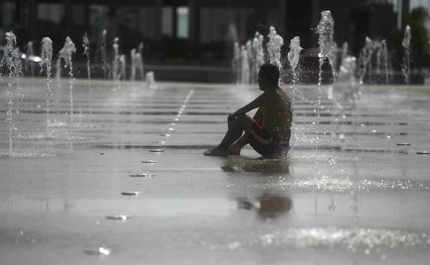 Un hombre se refresca en una fuente de Córdoba. 