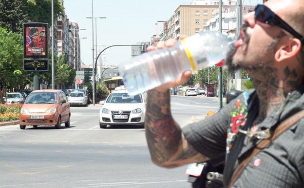 Un hombre bebe agua en una céntrica calle de Murcia a 42º. 