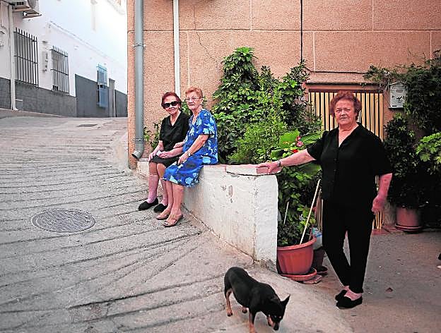 Vecinas de Coy miran curiosas a la cámara mientras toman el fresco, al atardecer, en la puerta de su casa. 