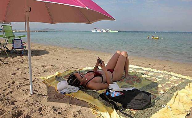 Una joven utiliza el móvil en Playa Mistral, en La Manga.