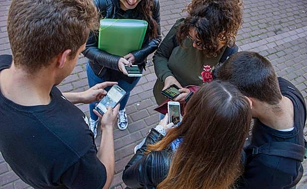 Un grupo de jóvenes consultan en los móviles su cuenta en las redes sociales.