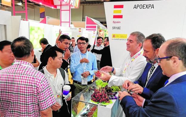 Javier Celdrán (2º dcha.) da a probar frutas en un expositor, ayer, en Asia Fruit Logistica de Hong Kong. 