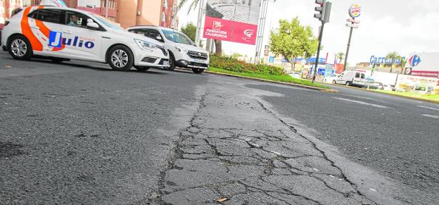 Dos coches, ayer por la mañana en la Plaza de Alicante, junto a un tramo de calzada con el asfalto resquebrajado. 