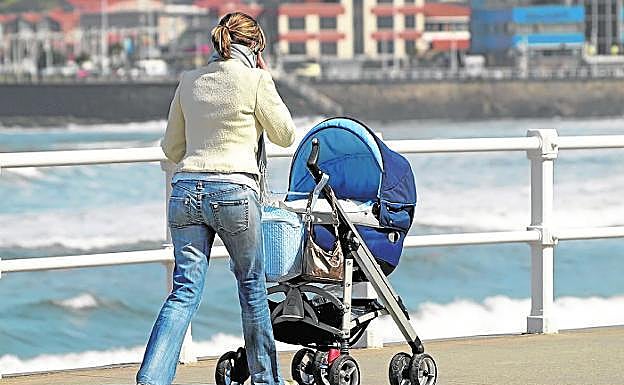 Una madre pasea a su bebé mientras habla por teléfono. /