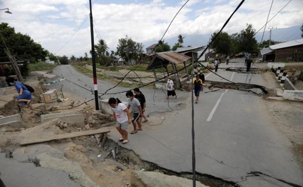 Varios lugareños caminan por las calles destruidas de Petobo, Palu. 