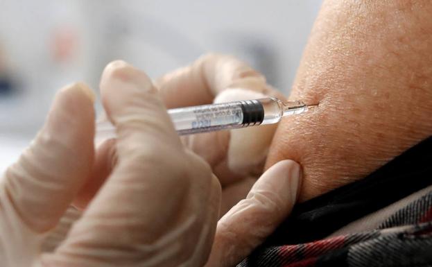 Un médico vacuna a un paciente al inicio de la campaña de vacunación contra la gripe.