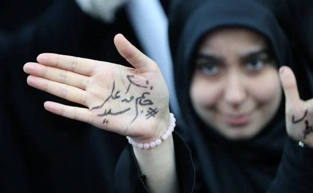 Una joven muestra un mensaje escrito en su mano que reza «estamos preparados para sacrificarnos por el Líder Supremo el Ayatola Ali Jameini» durante una manifestación convocada con motivo del aniversario de la toma de la Embajada de EE UU en Teherán.