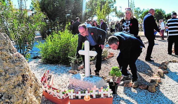 Dos vecinos depositan flores en el Jardín de la Memoria. 